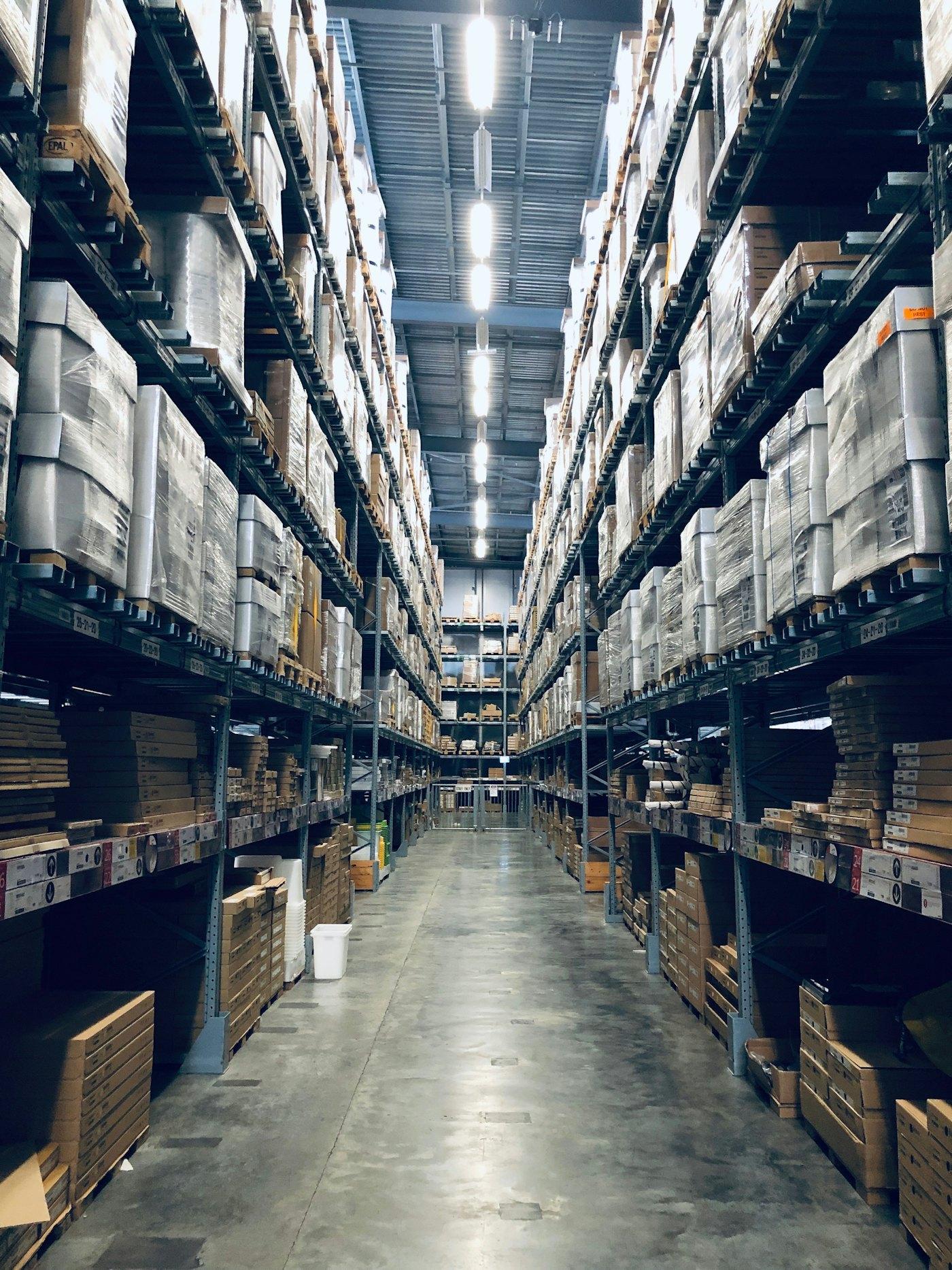 Long warehouse aisle lined with rows of identical boxed pallets